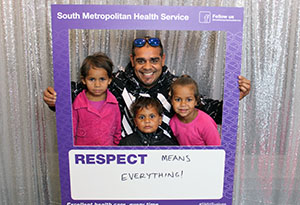 A man and three small children stand inside a frame that reads 'South Metropolitan Health Service: Respect'. A handwritten message on the board reads '... means everything.'