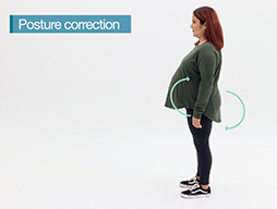 A pregnant woman with a good standing postuure - chin tucked in, shoulders down and back, stomach and bottom tucked in and weight distributed evenly on both legs.