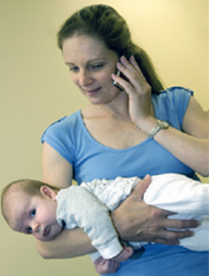 A woman holds carries a baby face down on her forearm with the baby’s head tucked in her elbow.