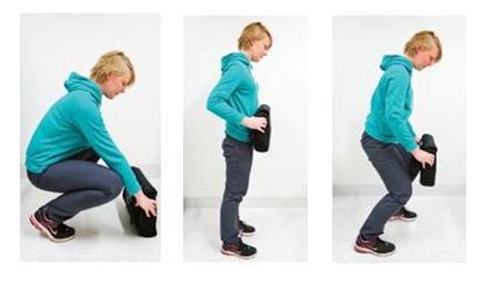 A woman demonstrates how to lift an item from the floor safely after back surgery in three photos.  The woman bends with her knees to lift an item on the floor. The woman then returns to a standing position with elbows at her side and the item close to her body. The women then moves her body by stepping her feet, not twisting.